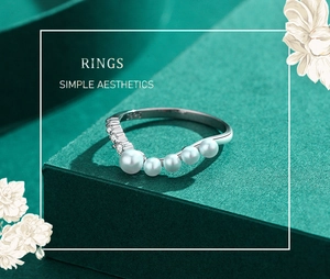 Detail of S925 sterling silver V-shaped ring with pearls and micro zircons on green stand