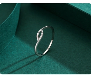 Close-up of a s925 silver cross ring with sparkling zircon stones on a green surface