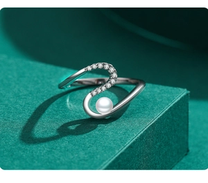 Détail macro d'une bague en argent en S avec cristaux scintillants et perle blanche élégante