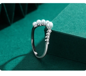 Macro side view of V-shaped S925 silver ring with white pearls and sparkling zircons