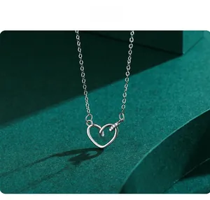 Gros plan du collier coeur évidé en argent S925 avec zircons sur fond texturé vert