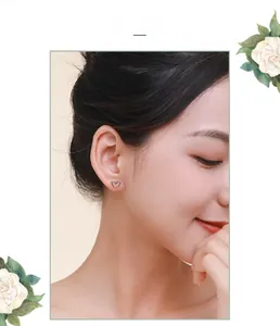 Close-up of minimalist s925 silver hollow heart stud earring worn by a model