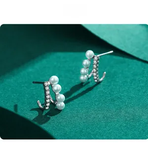 Detail of silver S925 earrings with rows of white pearls and sparkling cubic zirconia