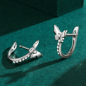 Elegant S925 sterling silver bow earrings with zircon stones on a dark green stand