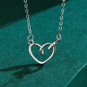 Élégant collier cœur évidé en argent s925 avec zircons sur tissu vert foncé texturé