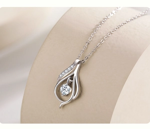 Macro shot of silver teardrop pendant featuring a dancing round stone and paved diamonds