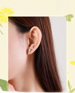 Detail of S925 sterling silver mini angel wing stud earrings with tiny gemstone on model
