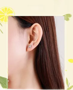 Close-up of minimalist s925 sterling silver butterfly stud earring on model's ear