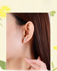 Close-up of S925 sterling silver apple stud earring worn on ear with polished finish