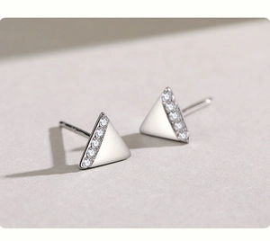 Dettaglio macro di orecchini a triangolo in argento S925 con pavé di zirconi e finitura lucida