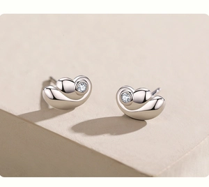 Macro shot of silver heart studs with round cubic zirconia in a polished bezel setting
