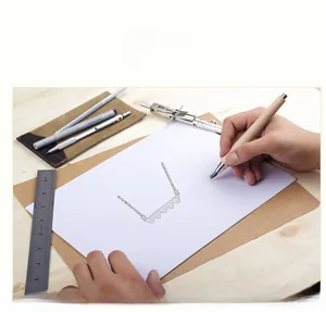 Croquis de conception d'un collier pendentif coeur en argent avec outils de dessin