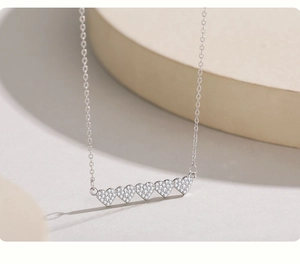 Vue macro d'un collier en argent 925 avec cinq cœurs étincelants sertis de zircons