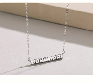 Détail macro du collier en argent S925 avec pendentif barre horizontale et zircons baguette