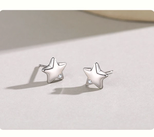 Macro shot of minimalist silver star earrings with a small cubic zirconia detail