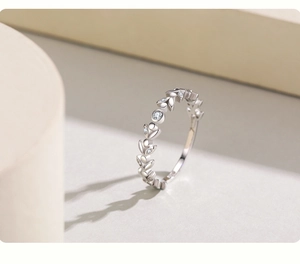 Détail macro de la bague pétales en argent S925 sertie de zircons sur fond minimaliste chaud