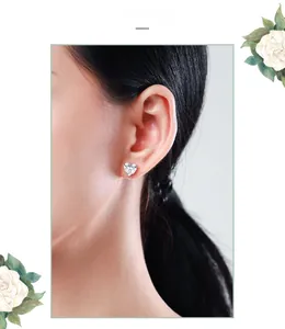 Detail view of heart-shaped silver stud earrings with sparkling stones worn by a model
