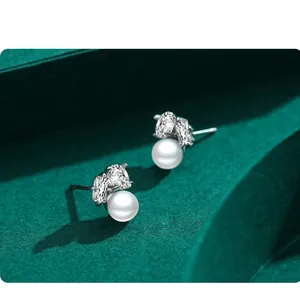 Detail shot of elegant S925 silver pearl earrings with marquise-cut zircons on green fabric