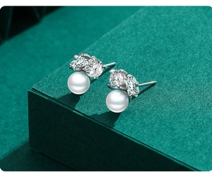 Macro shot of S925 silver pearl earrings with micro-inlaid rhinestones on green stand