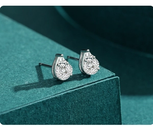 Macro shot of silver teardrop stud earrings with pavé zircons on a dark green jewelry box