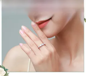 Close-up of s925 silver ring featuring pear-cut stones worn by a model in a floral setting