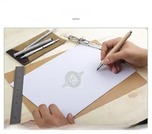 Macro design sketch of an oval 5ct diamond ring with drafting tools on a wooden desk