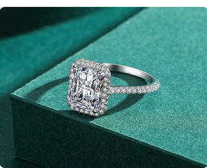 Macro detail of a halo-set rectangular zircon ring on a textured dark green surface