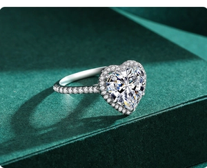 Macro shot of a heart-shaped diamond ring with halo setting and pavé band on green background