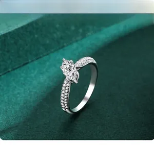 Vue macro de bague marquise avec serti pavé sur un fond texturé vert foncé