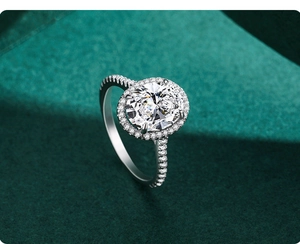 Vue macro d'une bague halo ovale avec diamants pavés sur un support texturé sombre