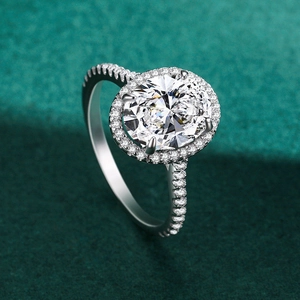Bague halo ovale en argent avec diamants pavés sur fond de velours vert élégant