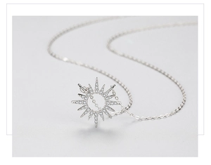 Macro shot of silver sunburst pendant with brilliant zircon pavé on a fine cable chain