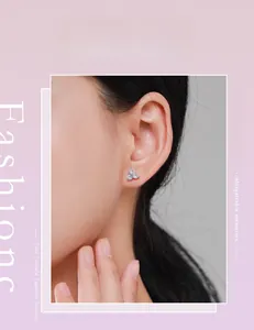 Close-up of sparkling S925 silver clover stud earrings worn by a model in soft lighting
