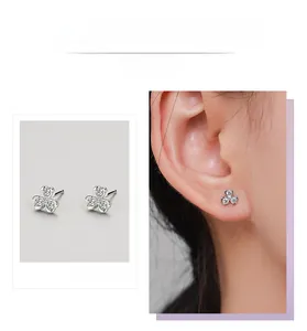 Detail view of silver clover stud earrings with clear zircon stones on a model ear