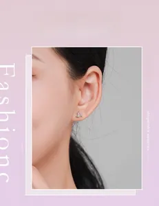 Detail of geometric S925 silver stud earring with a sparkling crystal on female ear