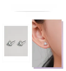 Detail display and model wearing silver triangle stud earrings with clear inlaid stones