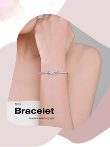 Macro detail of S925 silver clover bracelet featuring pink pear-cut stone on wrist