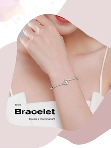Gros plan d'un bracelet cœur en argent s925 serti de diamants brillants sur le poignet