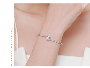 Gros plan du bracelet cœur en argent s925 avec pierre centrale et pavage micro sur un poignet