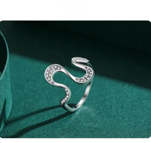 Detail of s925 silver wavy ring with micro-pave crystals on dark green ribbon background
