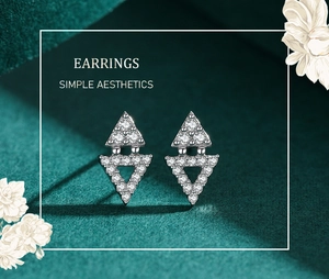 Detail of silver S925 triangle earrings with cubic zirconia on green velvet