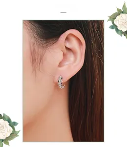Close-up of S925 sterling silver leaf hoop earrings with white zircon on a model