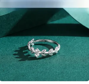Gros plan d'une bague feuille en argent S925 avec zircons sur fond vert texture