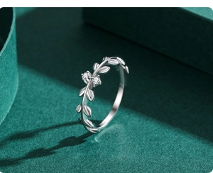 Vue macro d'une bague feuille d'olivier en argent avec zircons sur fond vert foncé