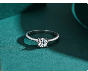Macro shot of 1 carat round moissanite silver ring on deep green elegant background