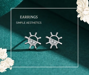 Macro shot of silver sunflower stud earrings with micro-inlaid zircon on green backdrop