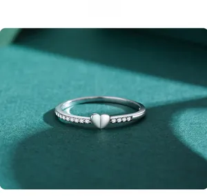 Macro shot of S925 silver heart ring with sparkling cubic zirconia on a green background