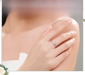 Detailed view of silver ring featuring round and rectangular cubic zirconia on finger