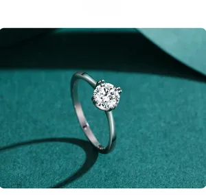 Close-up of a four-prong solitaire round cut silver ring on textured green background
