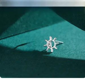 Close-up of S925 silver sunflower earrings with zircon stones on a dark green surface